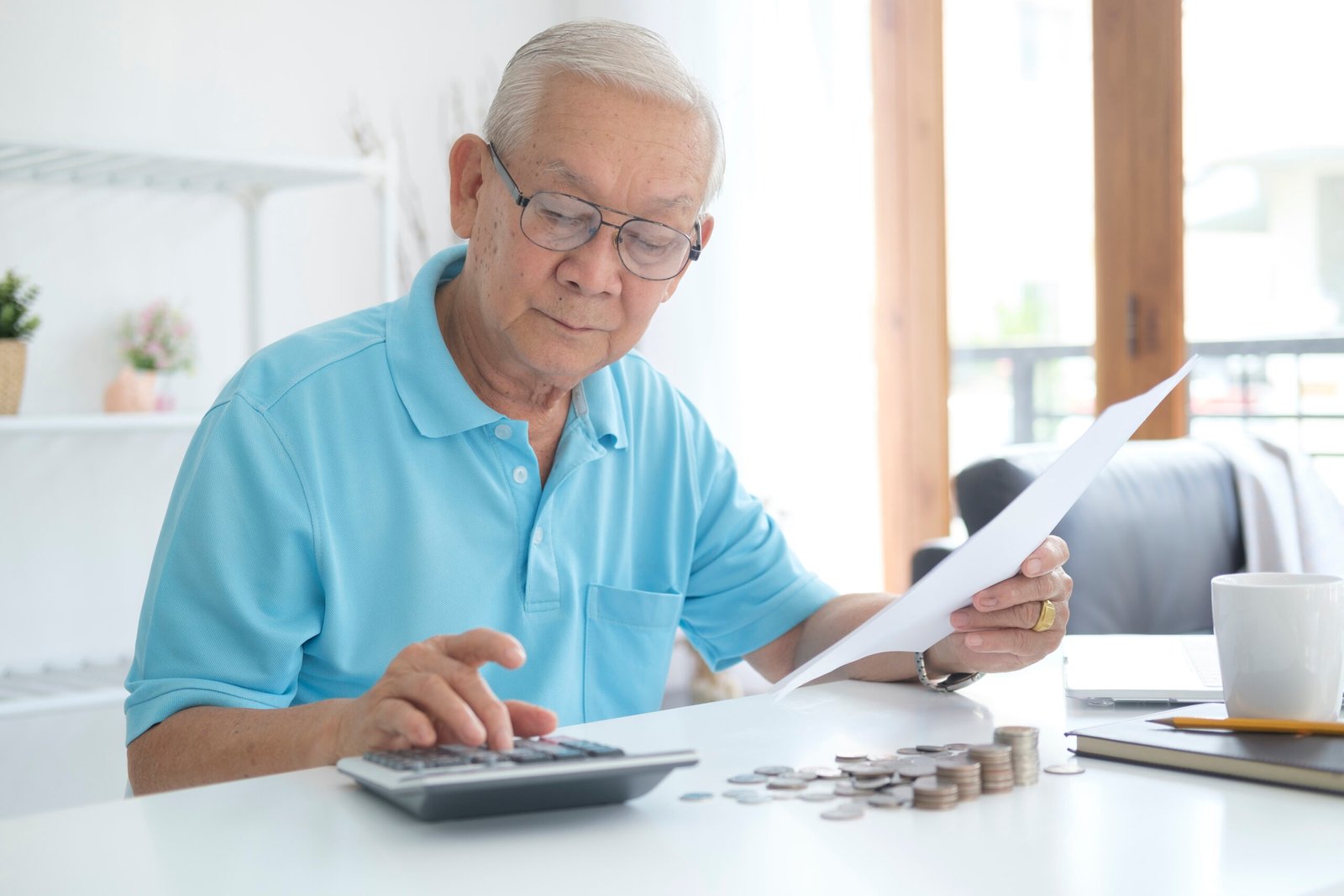 serious man sitting at table near utility bill and calculating e