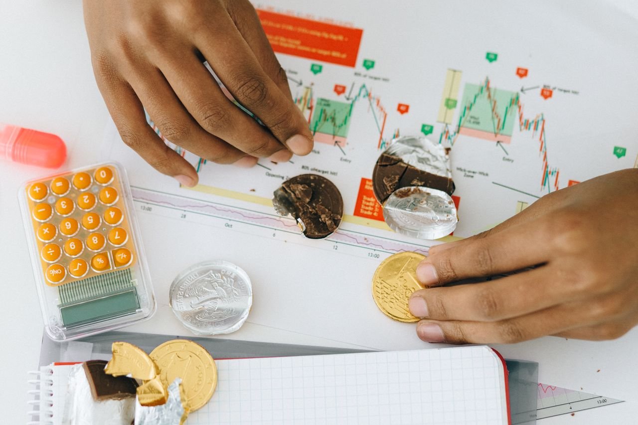 Analyzing financial charts with a calculator and chocolate coins.